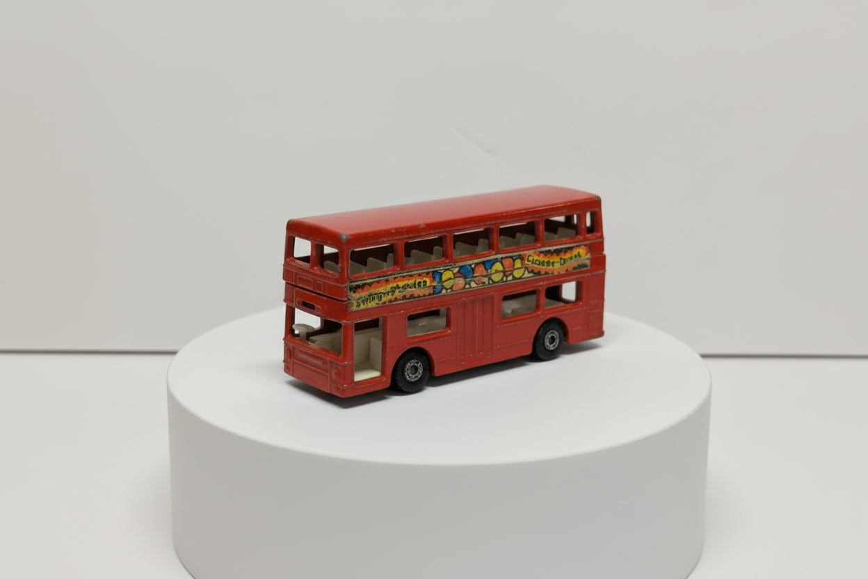 Red toy double-decker bus with colorful graphics on a white background