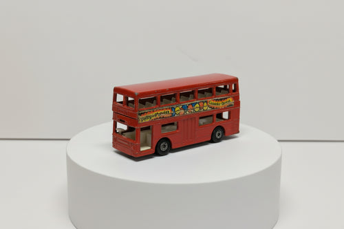 Red toy double-decker bus with colorful graphics on a white background