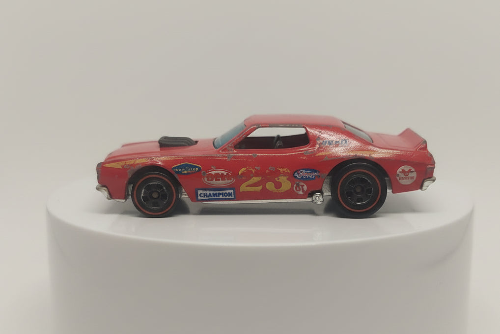 A pre-owned red Hot Wheels Redline model of a Ford Grand Torino with visible wear and tear.